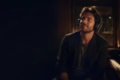 Why music affects emotions, shown by a listener absorbed in sound beside a piano and warm studio light.