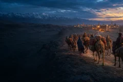 Silk Road caravan approaching a Central Asian oasis city at dusk
