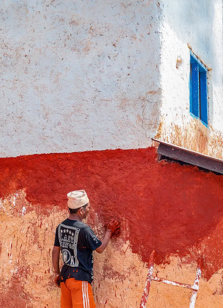 A man applying a fresh mud finish to a home before Dashain