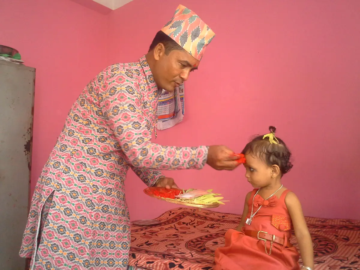 An elder giving Dashain tika and jamara to a child in Nepal