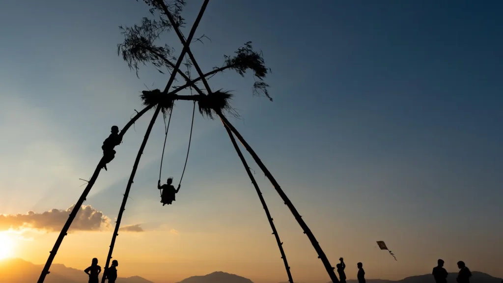 People on a bamboo swing during the Dashain festival in Nepal at sunset