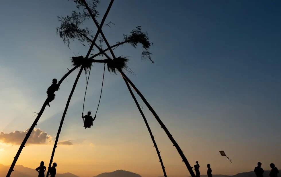 People on a bamboo swing during the Dashain festival in Nepal at sunset